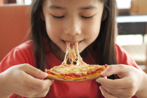Young girl enjoying a slice of pizza.